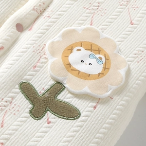 Detail of baby quilted jacket featuring a sunflower bear embroidery and soft fabric texture