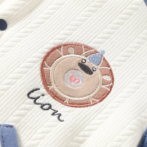 Détail du tissu tricoté matelassé blanc avec broderie lion et texte Lion