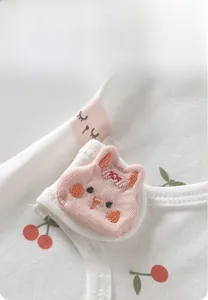 Détail de body bébé avec broderie cerise et fermeture velcro de haute sécurité