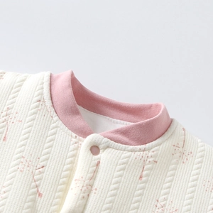 Detail of baby girl quilted cotton jacket neckline with pink ribbed collar and button