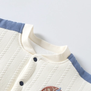 Détail du col en tricot pour bébé avec bord-côte et boutons-pression pratiques