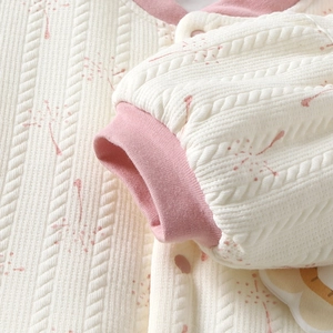 Close-up of quilted floral knit fabric with rib cuffs and pink buttons on baby cardigan