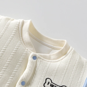 Macro-detail van een gebreid babyvest met ronde hals en blauwe drukknoopjes