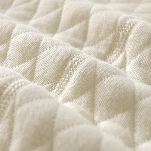 Detailed macro view of cream quilted thermal fabric with soft diamond stitching texture