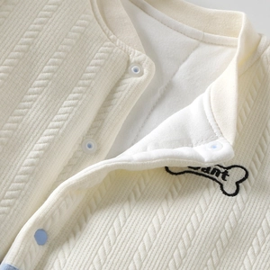 Detailopname van een crème gebreid babyvest met een ant-borduurwerk in botvorm
