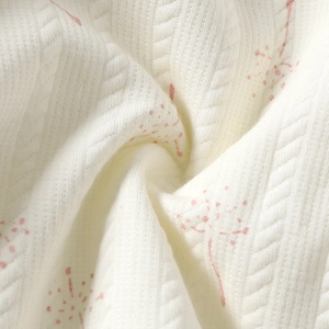 Detail of soft white jacquard knit fabric with pink floral patterns for baby sweaters