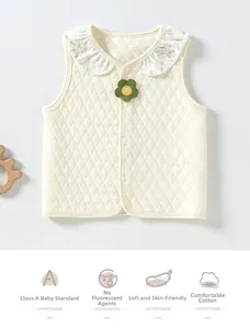Detail view of cream quilted baby vest with floral ruffle collar and green knit flower