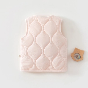 Detail of baby pink quilted puffer vest showing the soft wavy stitching and wash label