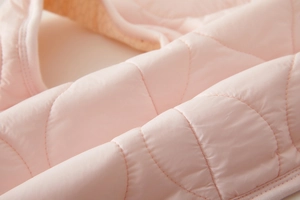 Close-up of light pink quilted fabric with wave stitching on this warm baby winter vest