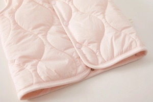 Close-up of pink quilted kids vest with wavy stitching and resin snap buttons detail