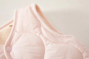 Close-up of pink quilted baby vest with detailed gourd patterns and animal embroidery