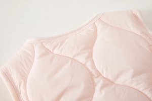 Detailed view of pink quilted baby vest with smooth stitching and soft collar texture