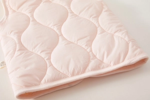 Detailed view of light pink quilted vest featuring gourd pattern and neat hem stitching
