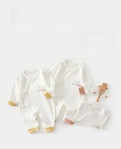 Détail d'une barboteuse pour bébé avec broderie ours et fermeture à nouer sur le côté