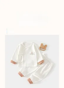 Detail of baby cotton pajama set with orange contrast trim and cartoon bear print