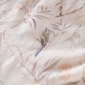 Gros plan sur le tissu en coton doux du bonnet bébé aux motifs délicats d'oiseaux