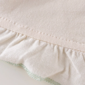 Détail du bonnet en coton pour bébé avec volants et bordure au crochet vert ondulé
