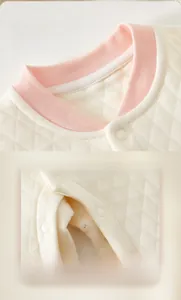 Detail of pink edged round neck and snap button closure on quilted infant romper