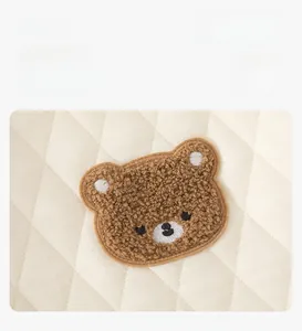 Détail du tissu matelassé pour bébé avec broderie d'ours en peluche 3D et motifs losanges