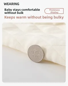 Détail du vêtement matelassé blanc pour bébé montrant la texture et l'épaisseur du tissu