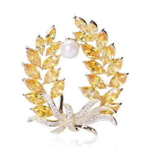 Detailed macro shot of a golden wheat brooch with sparkling zircons and a white pearl