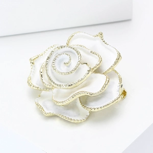 Vue macro de la broche camélia en émail blanc avec détails de bordure perlée dorée