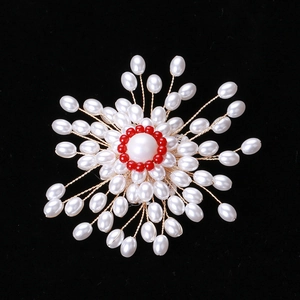 Vue détaillée d'une broche fleur faite main avec perles blanches et perles rouges