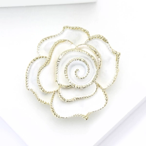 Détail de la broche camélia en émail blanc avec bords dorés pour un style élégant