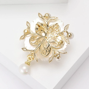 Broche camélia dorée avec pétales en nacre et perles blanches, vue arrière élégante