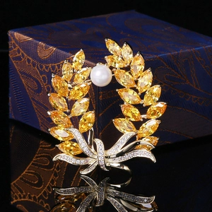 Detail of wheat stalk brooch with yellow marquise zircons and a white pearl on a gift box