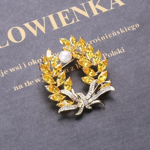 Close-up of wheat brooch featuring yellow marquise zircons and a round white pearl detail