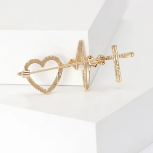 Broche dorée avec cœur, croix et ligne ECG présentant une texture en métal brossé