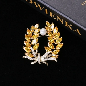 Macro detail of wheat ear brooch featuring yellow zircons and white pearl on black velvet