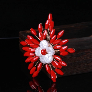 Detailed close-up of handmade red crystal beaded flower brooch with golden wire texture