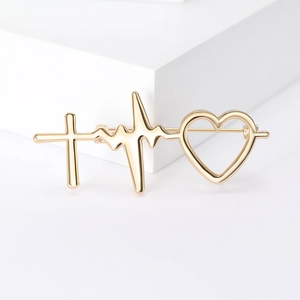 Broche minimaliste dorée avec battement de coeur, croix et coeur sur socle blanc