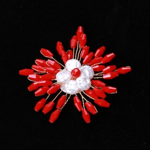Macro detail of handmade brooch featuring red faceted beads and white pearls in flower shape