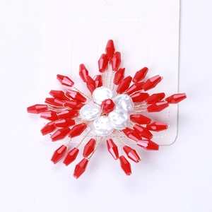 Detail of handmade beaded brooch with red crystals and pearls on white display card