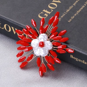 Macro detail of a handmade red crystal floral brooch with white pearls and gold wire