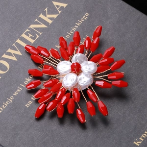 Handmade red crystal flower brooch with white pearls on a dark book background