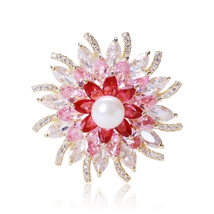 Détail macro d'une broche fleur 3D avec perle blanche, cristaux rouges et zircons