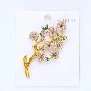 Détail macro de broche fleur de prunier avec pierres roses et feuilles en émail vert