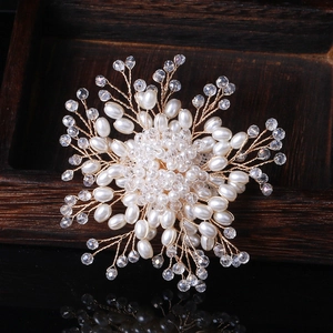 Detail einer handgefertigten Blumenbrosche mit weißen Perlen und Kristallen auf Golddraht