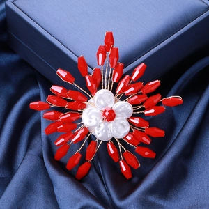 Detail of handmade red crystal flower brooch with white pearl center and gold wire craft