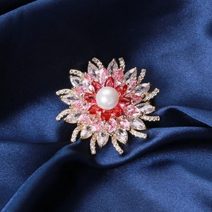 Vue macro d'une broche fleur en cristal avec pétales de zircon rouge et insert de perle