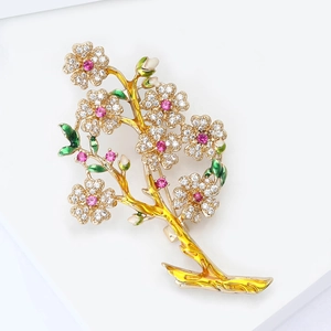 Broche branche de fleurs dorée élégante avec micro-zircons et gemmes roses sur fond blanc