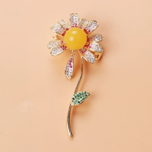 Macro detail of daisy brooch with gradient zircon stones and green enamel leaf