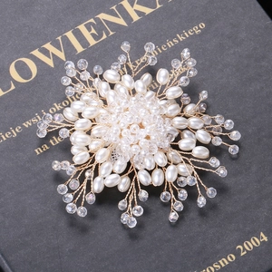 Elegante handgefertigte Perlenbrosche mit klaren Perlen und Golddraht auf Buch