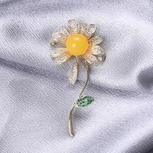Elegant daisy brooch with micro-paved zircons and amber centerpiece on grey silk fabric