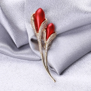 Luxurious gold tulip brooch with red buds and sparkling cubic zirconia on silk texture