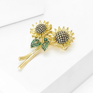 Elegante zonnebloem broche met gele zirkoon blaadjes en groene details op een voetstuk